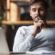 Man sitting back in a chair, looking confused at his computer screen. 